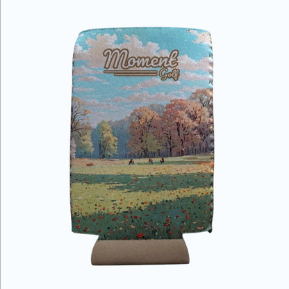 Moment Golf slim can koozie featuring an autumn landscape print and A Never Ending Pursuit text on a cream background.