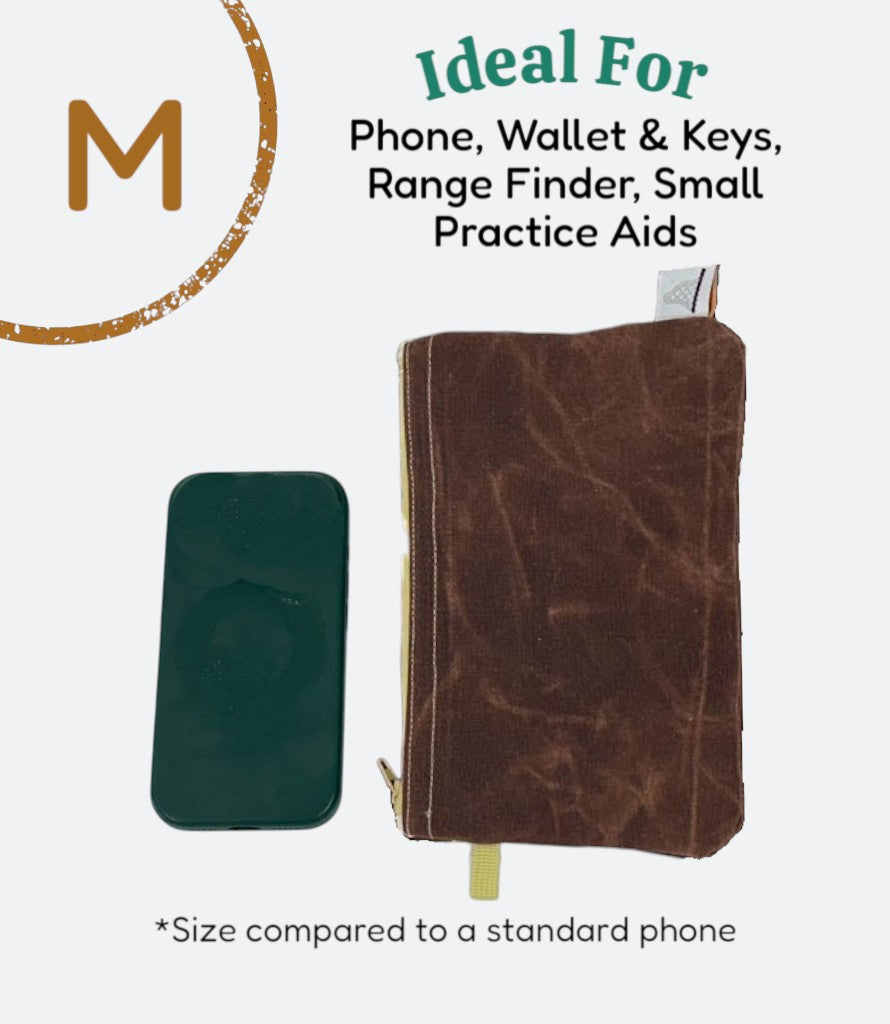 Moment Golf medium utility bag in blue waxed canvas with drawstring closure next to a smartphone for size reference