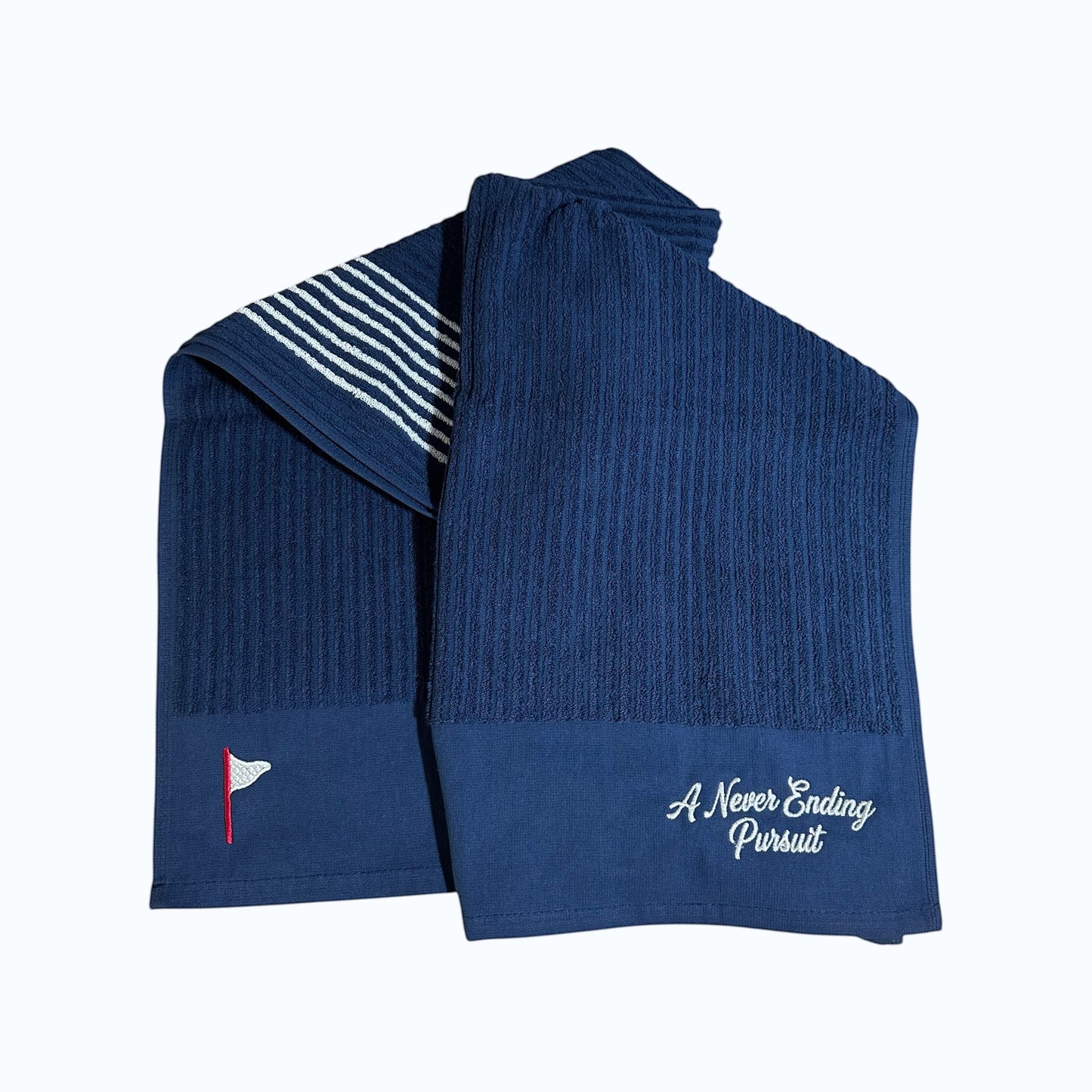 Moment Golf navy blue striped cotton caddy towel with embroidered flag logo and A Never Ending Pursuit text