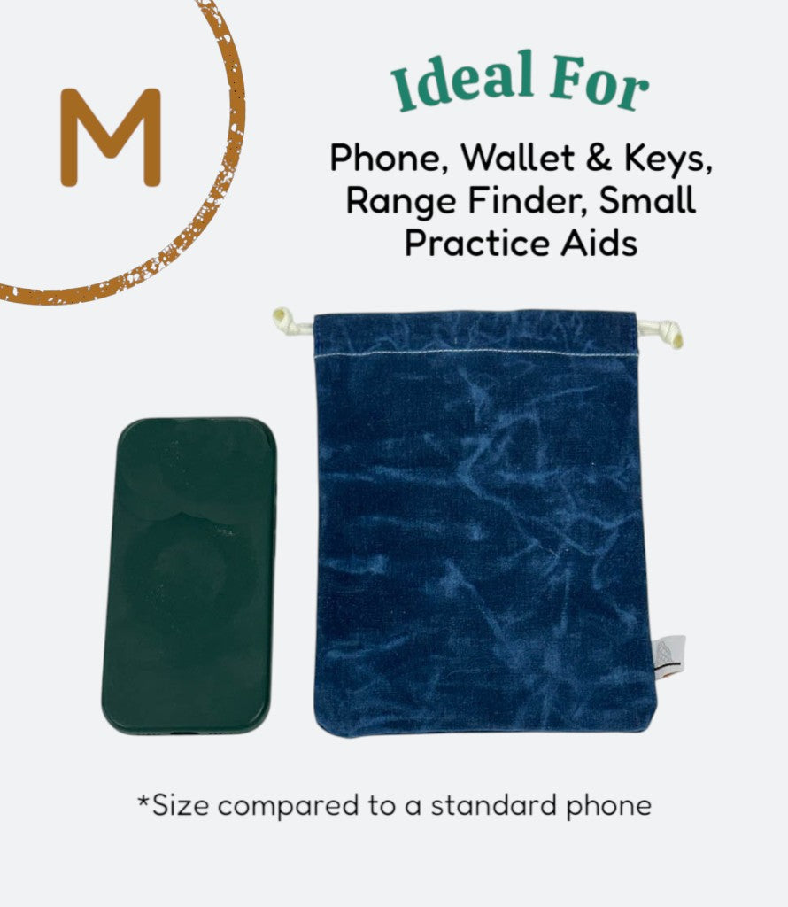 Moment Golf small blue waxed canvas utility bag with drawstring closure next to a smartphone for size reference